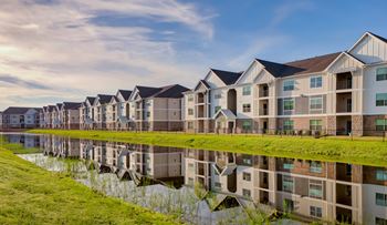 A row of modern houses are reflected in the water in front of them.